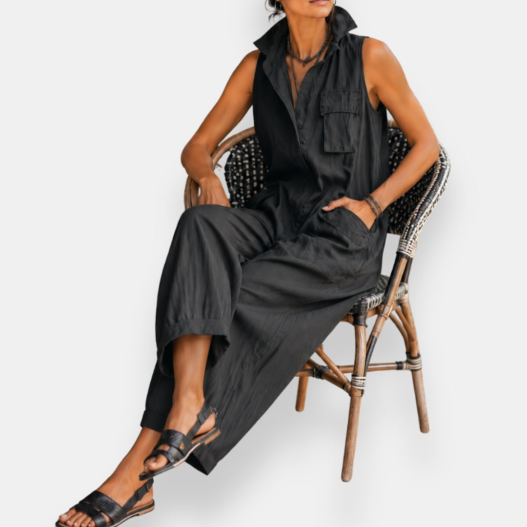 Rowan Sleeveless Utility Jumpsuit — Black, seated — showing the drape